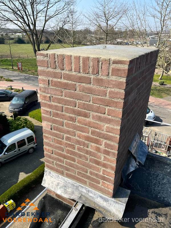 Gemetselde schoorsteen met loodaansluiting op dak in Voerendaal Gemetselde schoorsteen met loodaansluiting op dak in Voerendaal