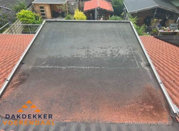 Verouderd plat dak met slijtage tussen schuine daken in Voerendaal Verouderd plat dak met slijtage tussen schuine daken in Voerendaal