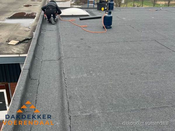 Dakdekker repareert bitumen dakbedekking op groot plat dak in Voerendaal